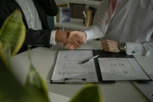 deux personnes se serrant la main au-dessus d'un morceau de papier