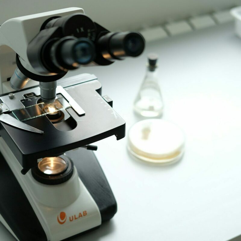A microscope sitting on top of a table next to a bottle